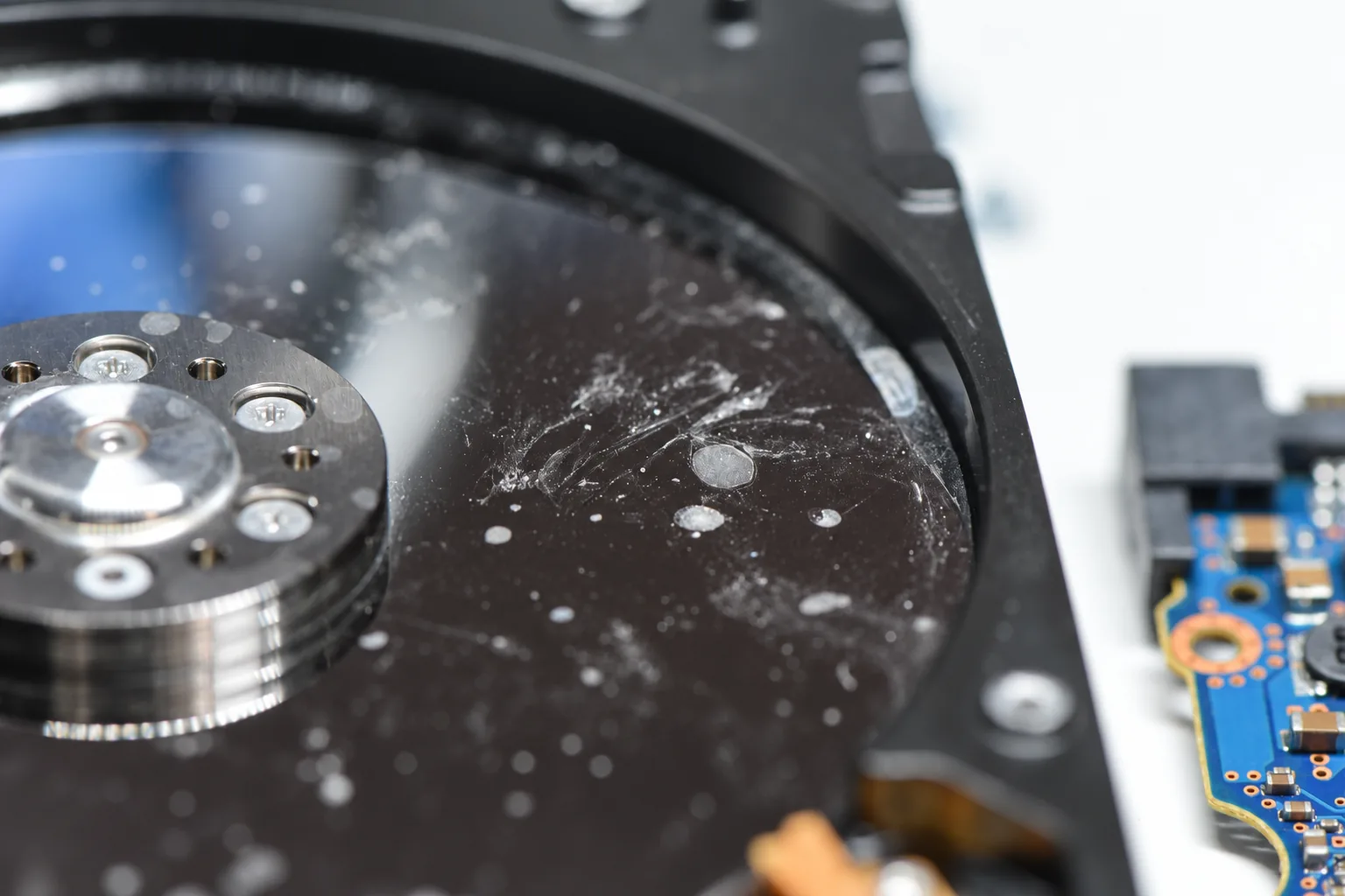 Close-up of contamination deposits and residue on a water-damaged hard drive platter surface