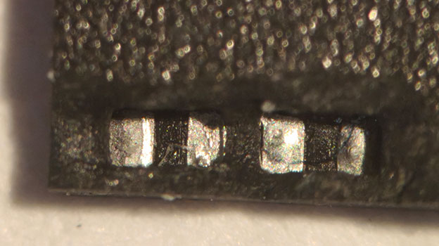 Microscope close-up of failed capacitors on a monolithic SD card during data recovery diagnostics